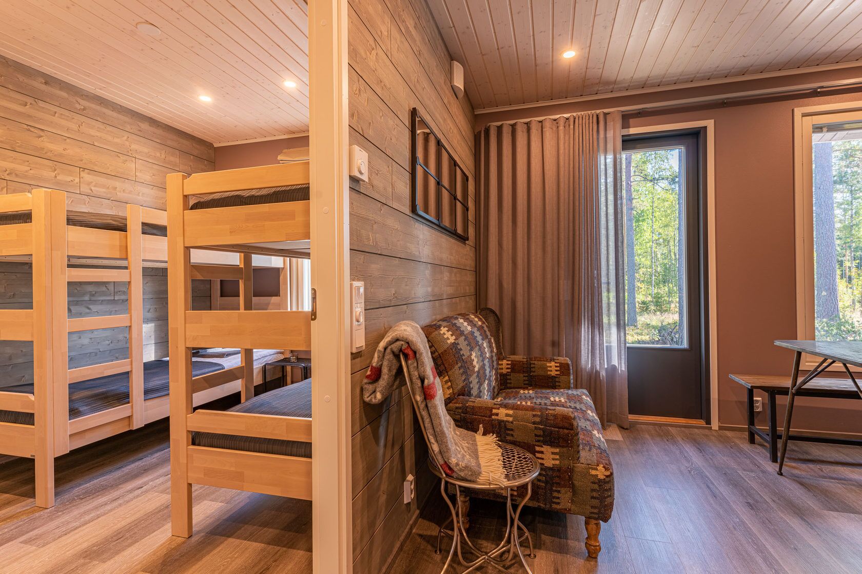 A cozy cabin interior with wooden bunk beds, a cushioned seating area, and a dining table.