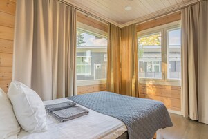 Un dormitorio con cama, cortinas y vista a una casa a través del ventanal.