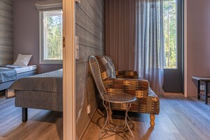 Una habitación acogedora con una cama, un sillón estampado y una ventana con cortinas.