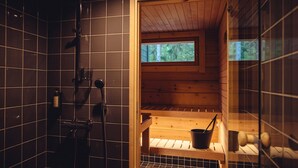 A sauna with a wooden bench, a bucket, and a window.