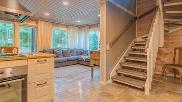 A modern kitchen with a built-in oven, a dining area with a wooden table, and a staircase leading to an upper level.