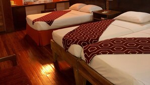 A hotel room with two beds, a desk, a chair, and a mirror. - Monique's Guesthouse (Port of Spain)