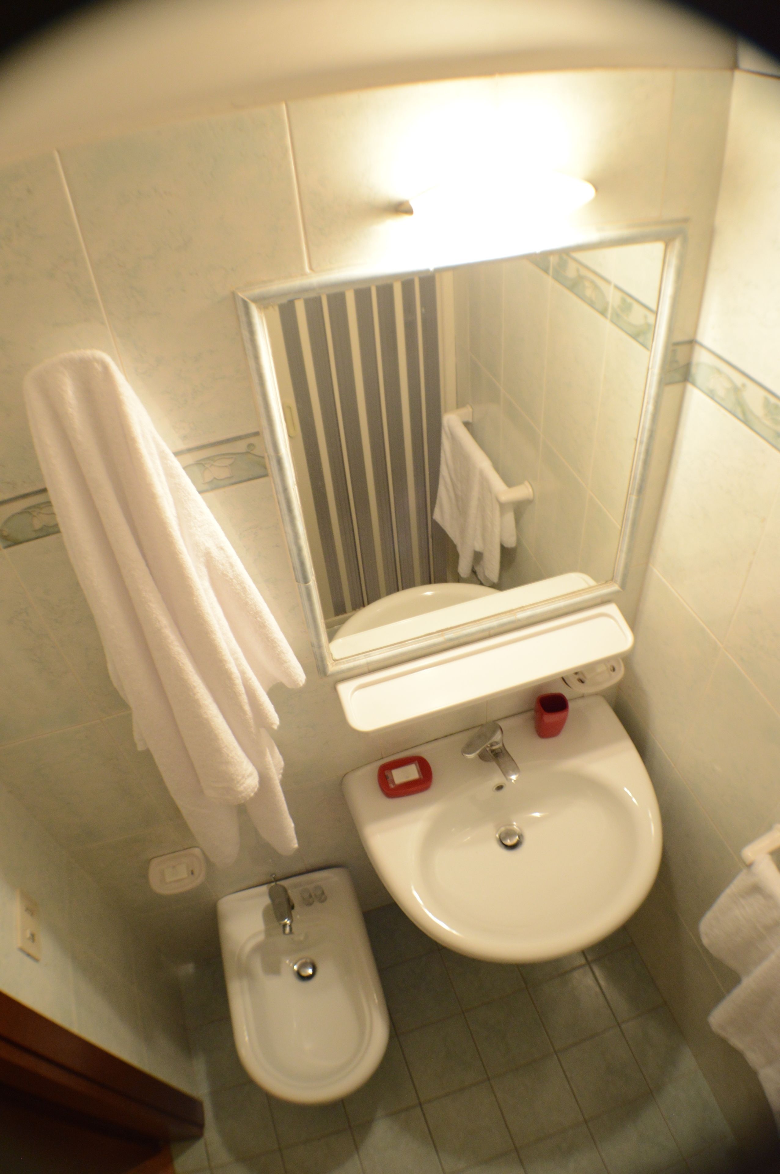 A bathroom with a toilet, bidet, sink, and a mirror.