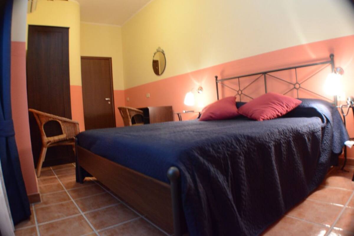 A bedroom with a bed, a chair, a desk, and a door.