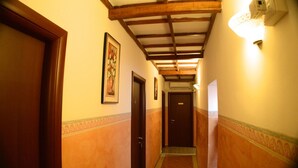 Un corridoio con porte in legno, un quadro appeso al muro e un lampadario.