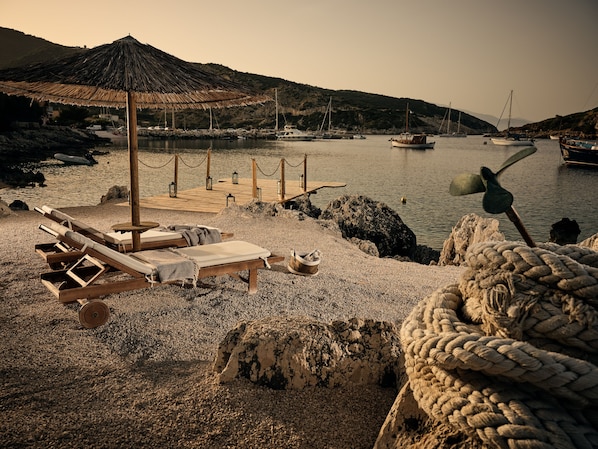 A beach with lounge chairs, a wooden deck, and a rope barrier.