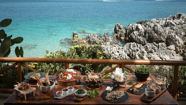 A dining table with various dishes and a view of the ocean. - Nobelos Seaside Lodge (Zakynthos)