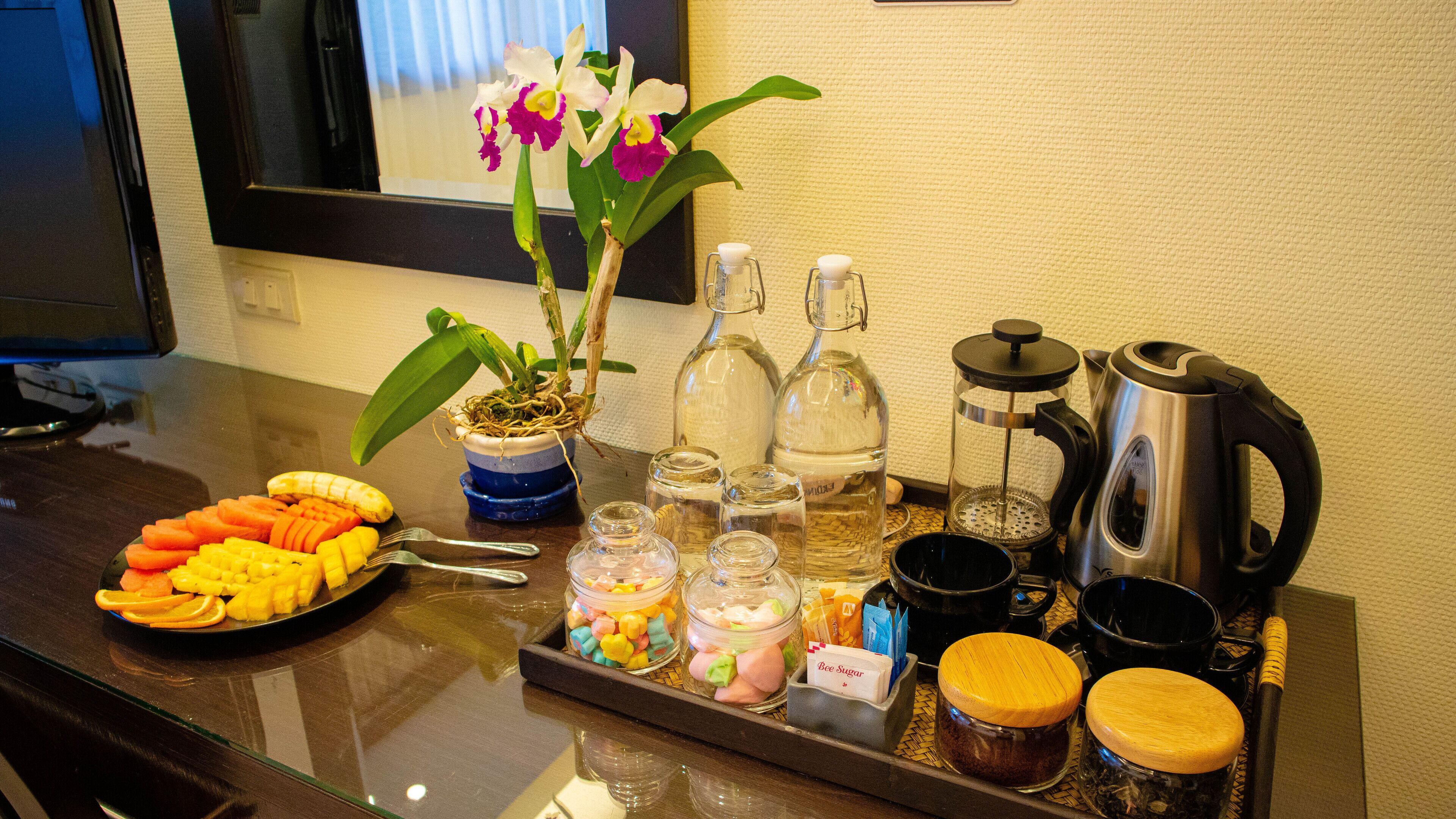 Bandeja de desayuno con frutas, salsas y una cafetera sobre una encimera de hotel.