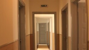 A hotel hallway with a carpeted floor, wooden doors, and a sign above the door. - Be Coimbra Hostels (Coimbra)