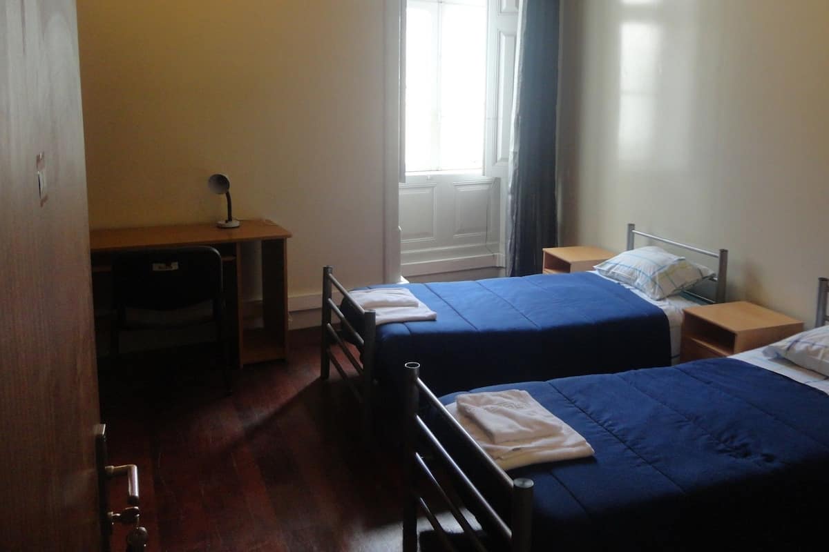 A room with two beds, a desk, and a chair.