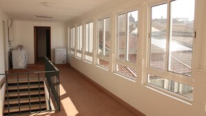 A corridor with a staircase, large windows, and a view of rooftops. - Be Coimbra Hostels (Coimbra)