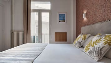 Habitación de hotel con una cama grande, vista al exterior, un cuadro enmarcado en la pared y una pared decorativa de ladrillo.