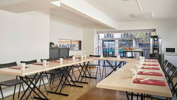 A conference room with long tables, chairs, and a kitchenette area.