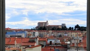 A cityscape with a prominent historical building on a hill, surrounded by residential buildings with red-tiled roofs. - The Originals City, Hôtel Mondial, Perpignan (Perpignan)