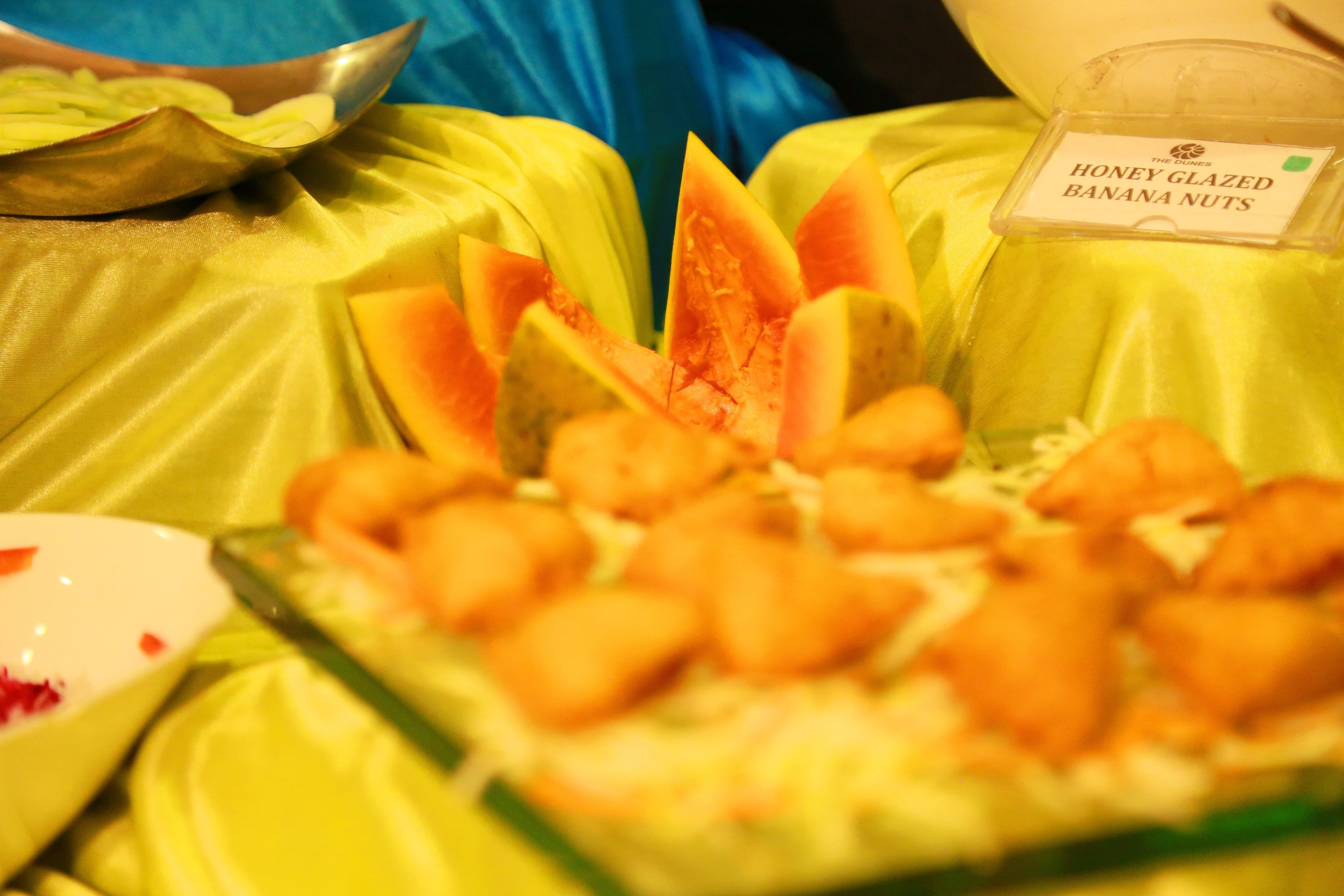 Ein Tisch mit einer Schale Honig-Banananüsse und einem Behälter mit der Aufschrift 'HONEY GLAZED BANANA NUTS'.