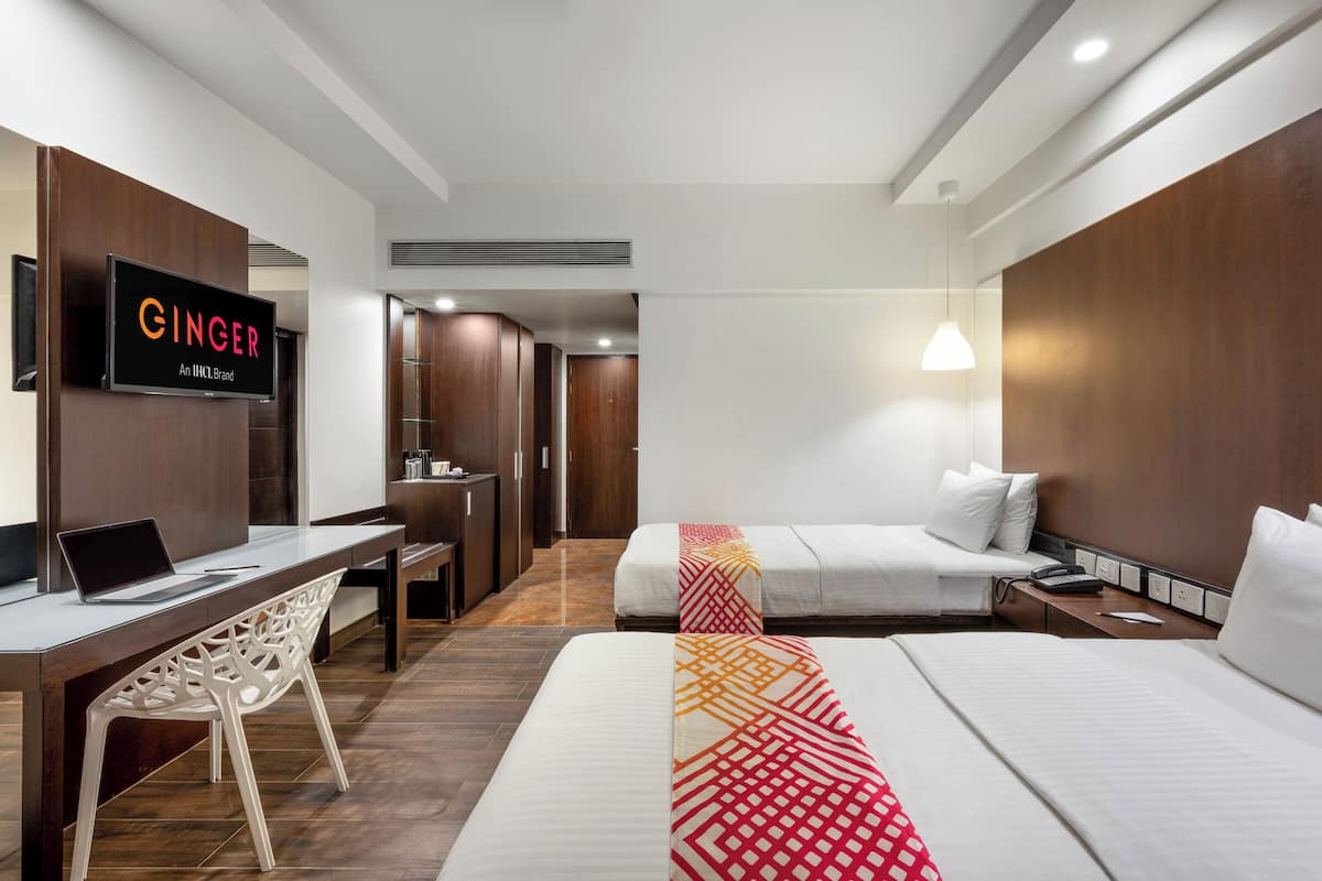 A hotel room with a desk, a bed, and a TV displaying the brand name.