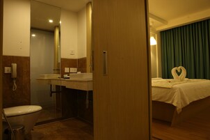 A hotel bathroom with a toilet, sink, and mirror.