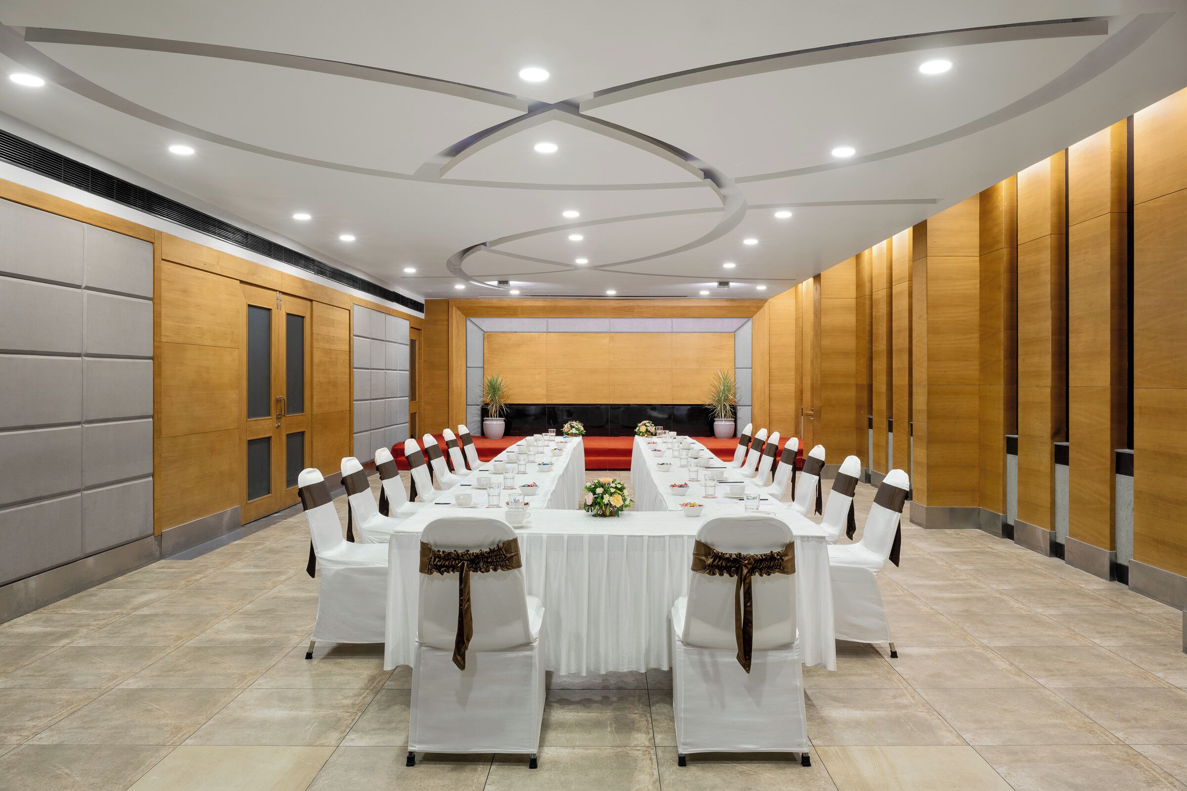 A conference room with a long table, white chairs, and a red carpet.