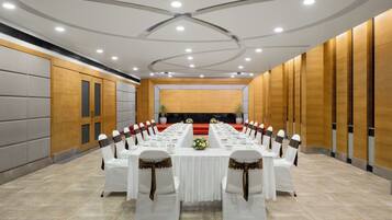 A conference room with a long table, white chairs, and a red carpet.