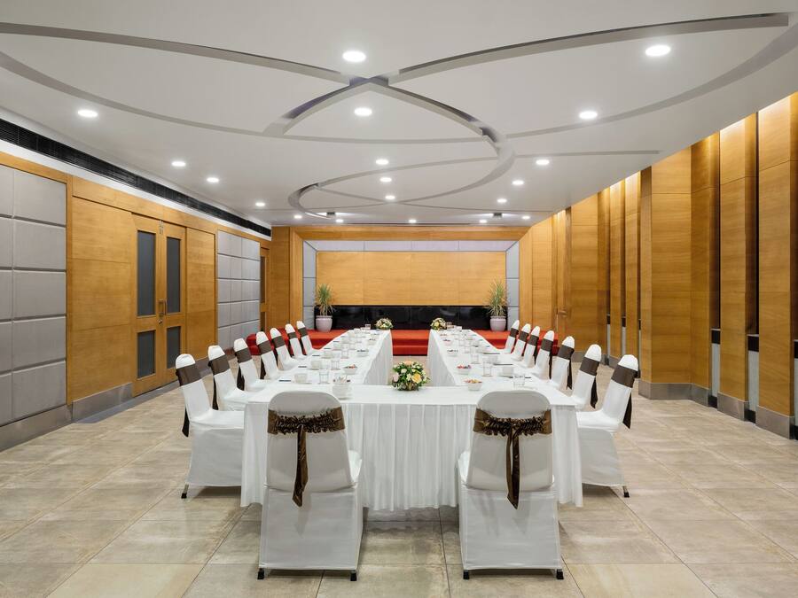 A conference room with a long table, white chairs, and a red carpet.