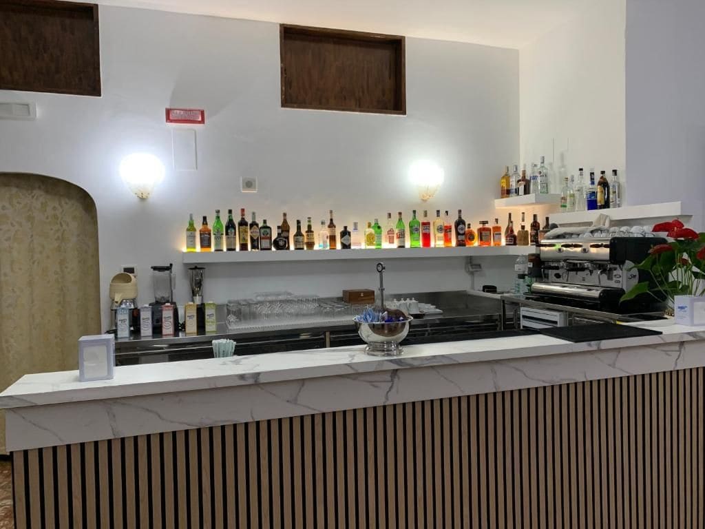 A bar area with a marble countertop, various liquor bottles, a coffee machine, and a decorative bowl.