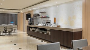 Un hall d’hôtel moderne comprenant un comptoir d’accueil, un espace salon et un coin café.