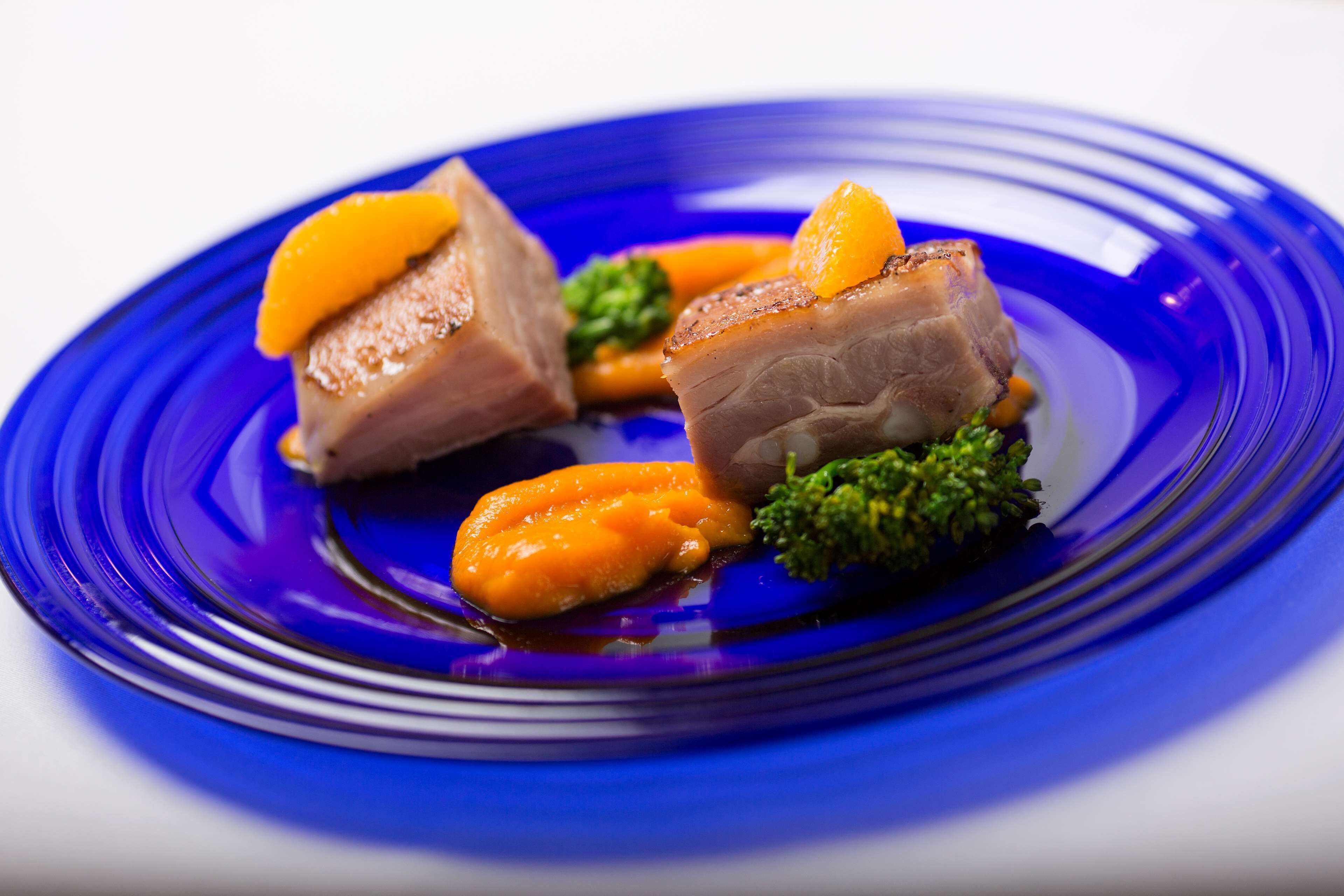 A plate with meat, orange slices, and broccoli.