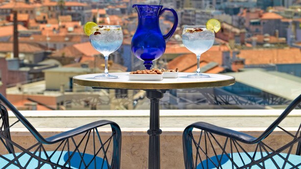 Una mesa con dos bebidas y una jarra, con vista a un paisaje urbano.