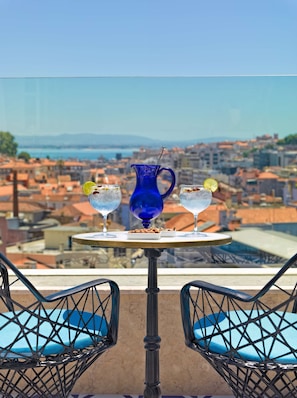 Una mesa con dos bebidas y una jarra, con vista a un paisaje urbano.