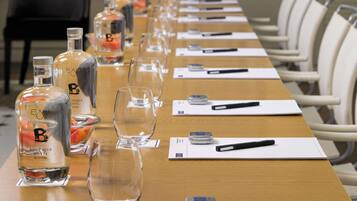 A conference room with a long table set for a meeting, featuring bottles of water, glasses, and notepads.