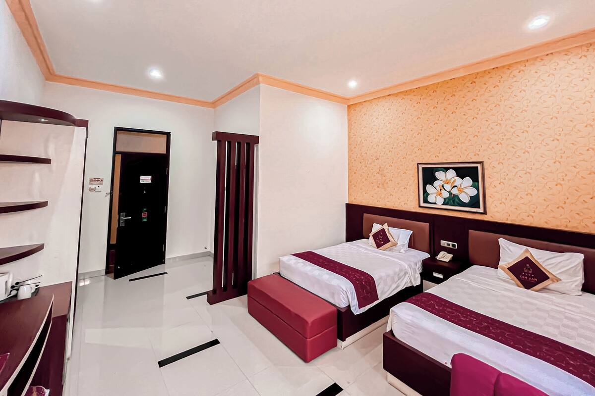 A hotel room with two beds, a wardrobe, a desk, and a bathroom.