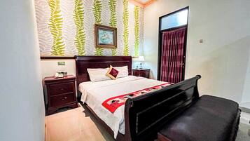 A bedroom with a bed, a nightstand, a dresser, and a desk.