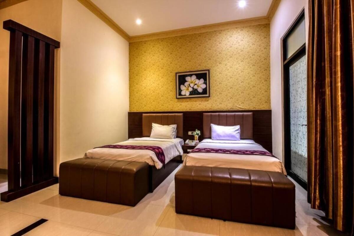 A hotel room with two beds, a large window, and a floral artwork on the wall.