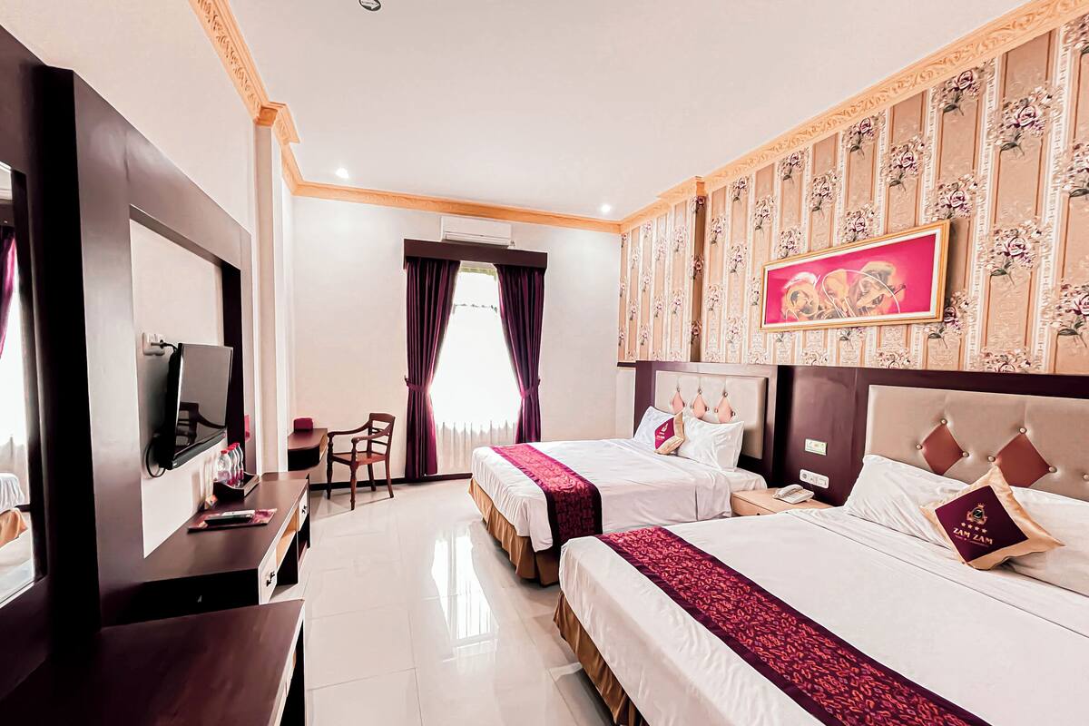 A hotel room with two beds, a TV, a desk, and a chair.