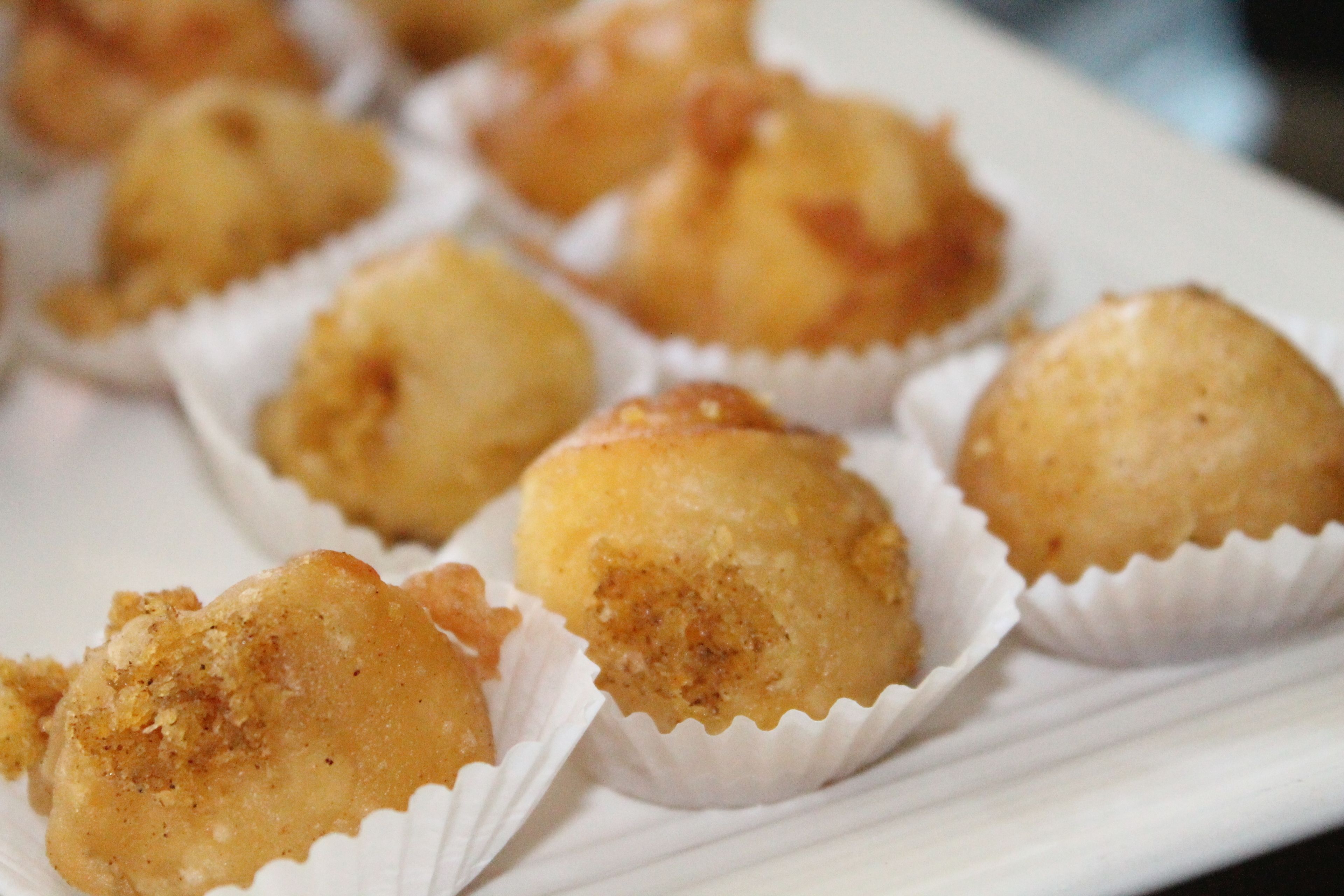 A tray of round, golden-brown pastries in paper cups.