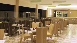 A restaurant with wicker chairs and tables, a checkered floor, and a glass railing overlooking a garden. - Zamzam Hotel and Convention Batu Powered by Archipelago (Batu)