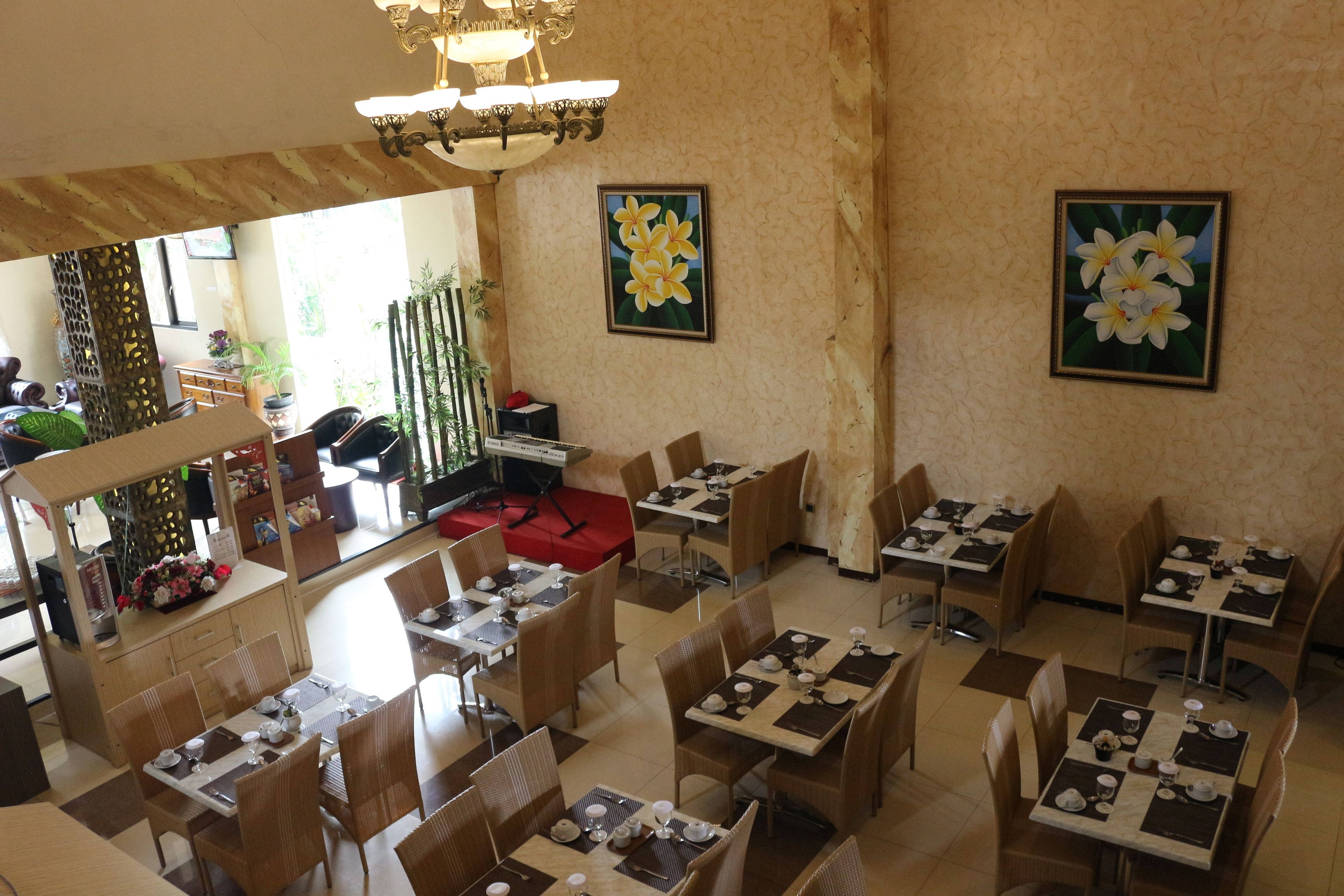Un restaurante con varias mesas y sillas, una zona de bar y dos cuadros enmarcados con motivos florales en las paredes.