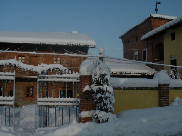 Um edifício coberto de neve com fachada de tijolo e uma parede amarela.
