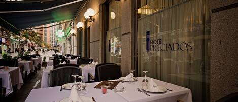 A restaurant with tables set for dining, a menu, and a sign reading "HOTEL PRECIADOS".