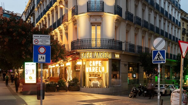 A multi-story hotel with a curved facade, balconies, and a cafe at the ground level. - Hotel Preciados (Madrid)