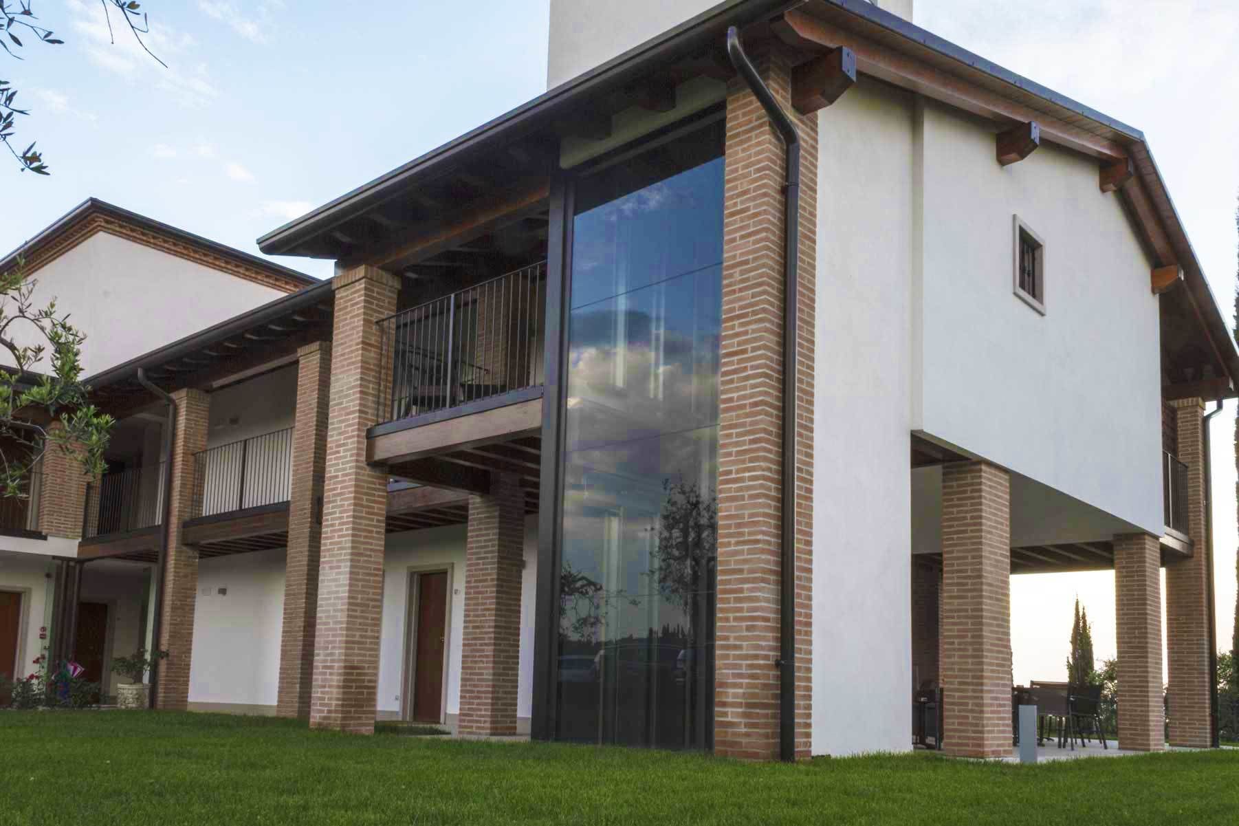 A modern two-story building with a balcony, large windows, and a brick facade.