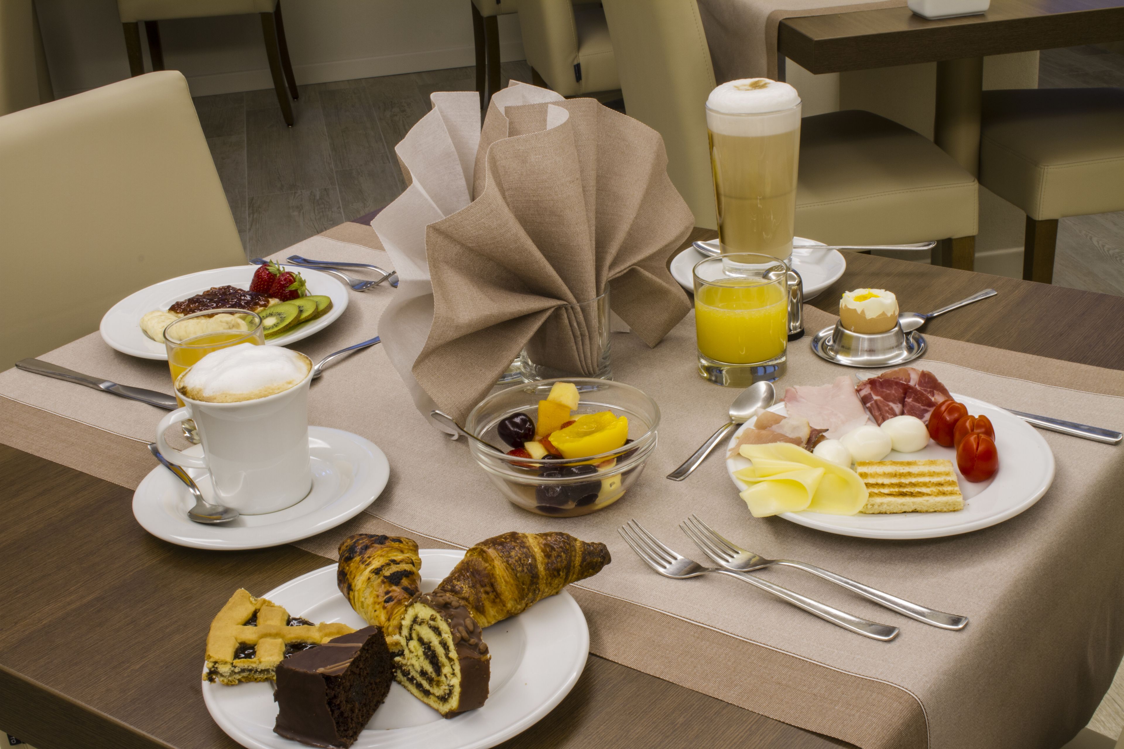 Una mesa de desayuno con platos de comida, un vaso de jugo de naranja y una taza de café.