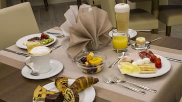 Una mesa de desayuno con platos de comida, un vaso de jugo de naranja y una taza de café.