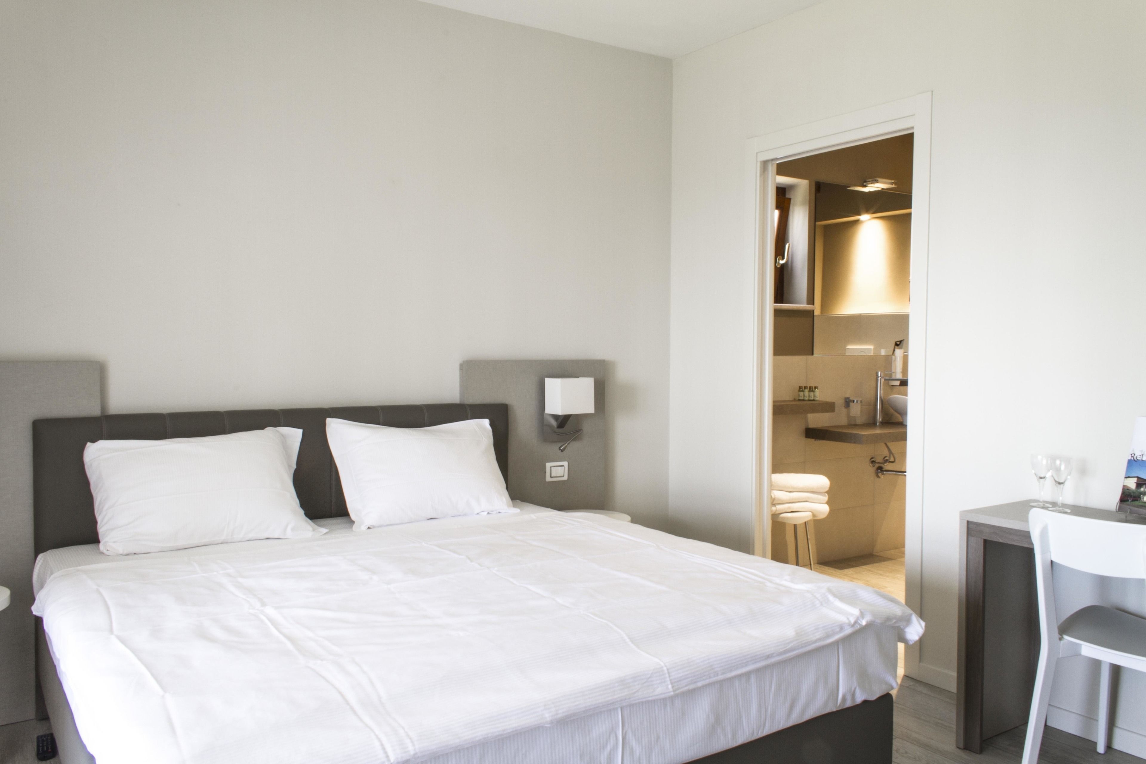 Ein Hotelzimmer mit Bett, Nachttisch und kleinem Schreibtisch mit Stuhl.