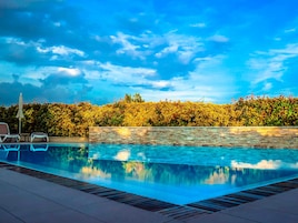 Una piscina al aire libre, sombrillas, sillones reclinables de piscina