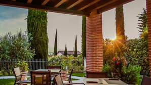 Un patio al aire libre con columna de ladrillo, pérgola de madera y zona de estar.