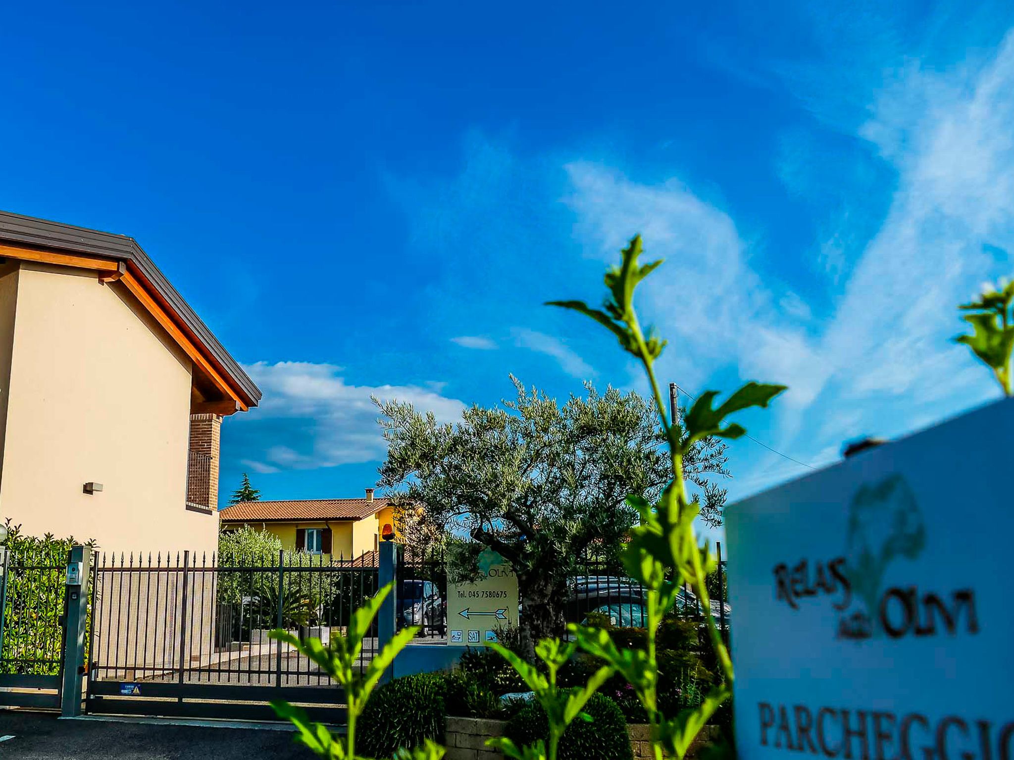 Un edificio con fachada color beige, techo rojo y una entrada protegida por una reja.
