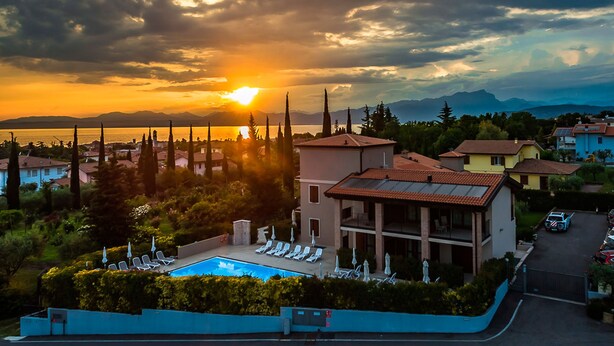 Un resort con piscina, sillas de descanso y vistas a la puesta de sol sobre un lago.