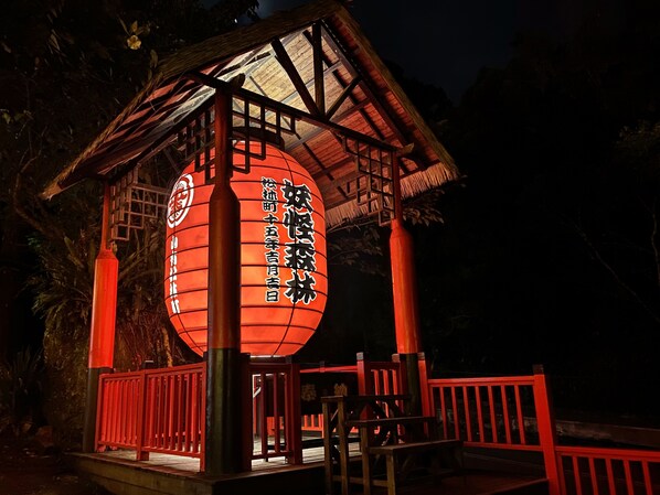 A traditional Japanese lantern with Chinese characters, mounted on a wooden structure with a red railing.