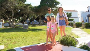 Una familia caminando por un sendero pavimentado en un parque con césped y árboles.